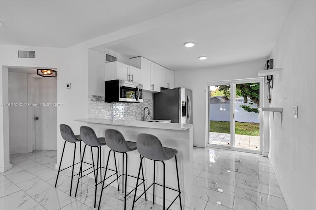 kitchen with visible vents, appliances with stainless steel finishes, white cabinetry, marble finish floor, and backsplash