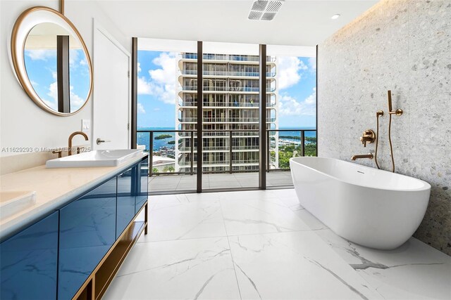 bathroom featuring a washtub, a healthy amount of sunlight, a wall of windows, a water view, and vanity