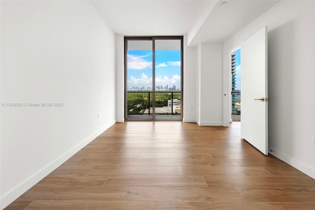 empty room with light hardwood / wood-style floors and a wall of windows