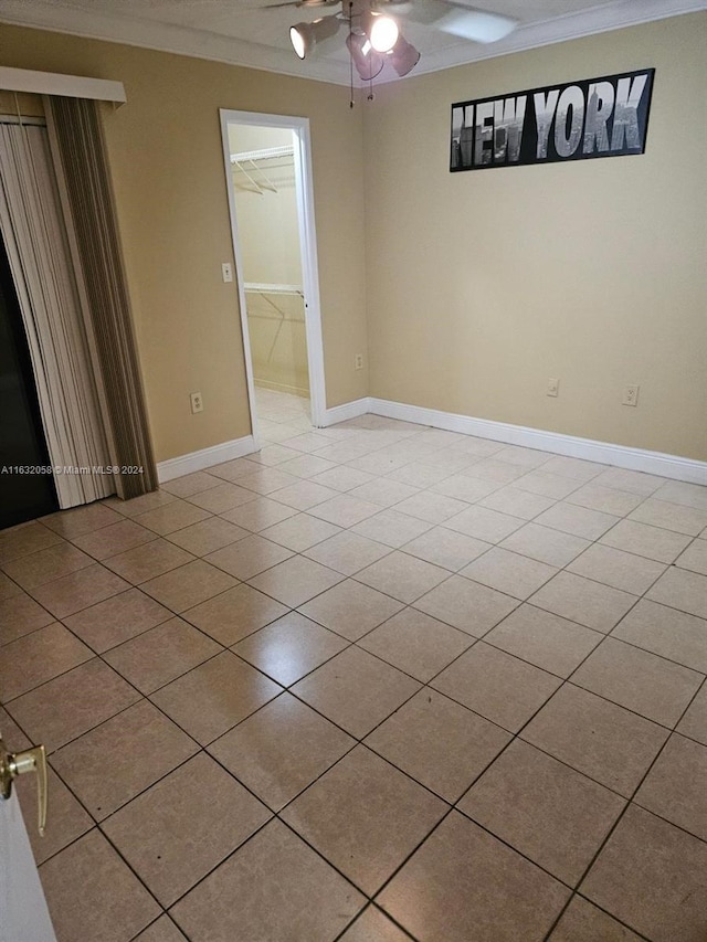 unfurnished room featuring ceiling fan, ornamental molding, and light tile patterned flooring