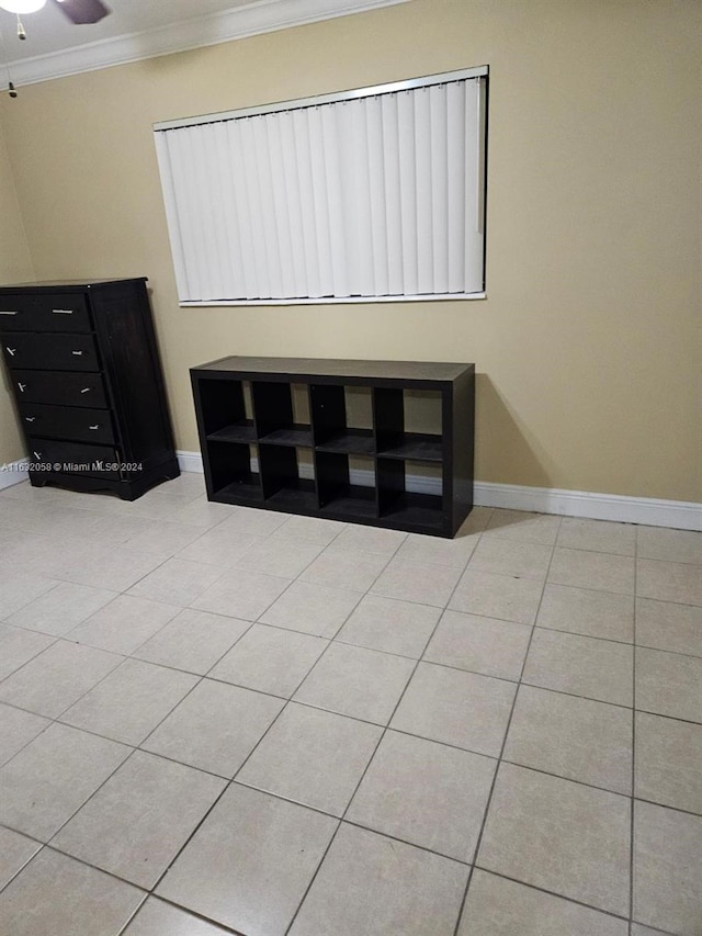 empty room featuring ceiling fan, light tile patterned flooring, and crown molding