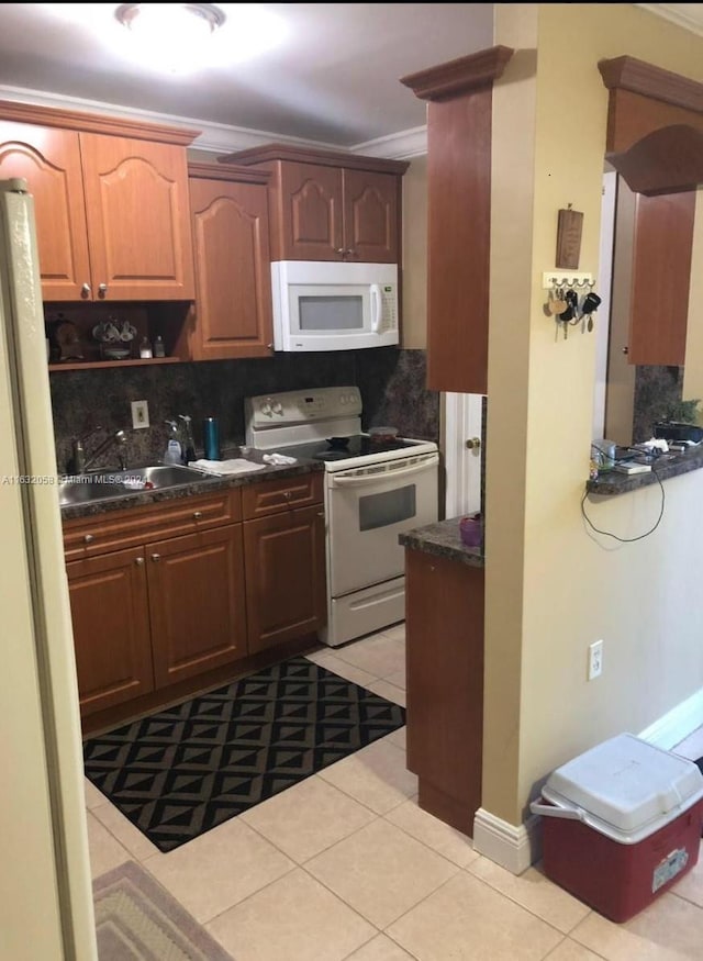 kitchen featuring backsplash, sink, light tile patterned flooring, and white appliances