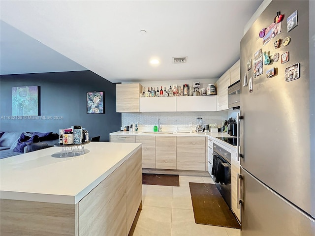 kitchen featuring light tile patterned flooring, a center island, stainless steel appliances, light brown cabinetry, and sink