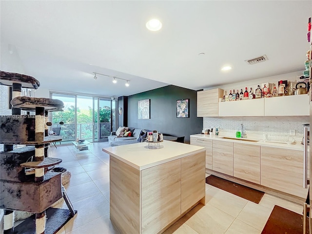 kitchen with light tile patterned flooring, a center island, track lighting, light brown cabinetry, and sink