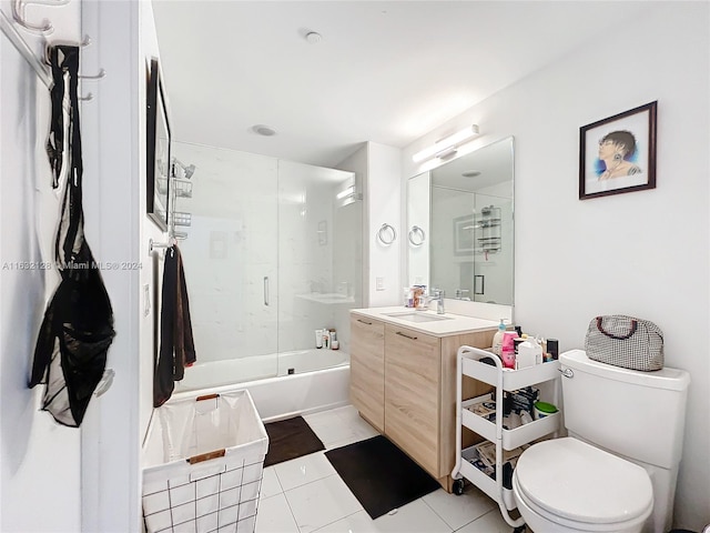 full bathroom featuring combined bath / shower with glass door, tile patterned floors, toilet, and vanity