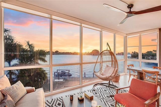 sunroom / solarium with ceiling fan and a water view