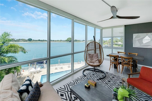 sunroom / solarium featuring ceiling fan and a water view