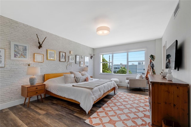 bedroom with dark wood-type flooring and brick wall