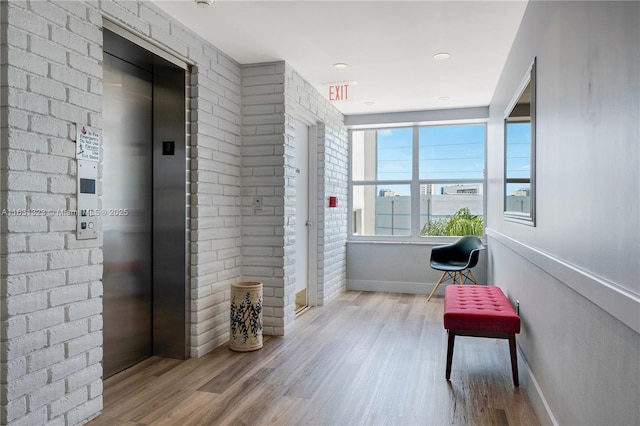 corridor featuring light wood-type flooring and elevator