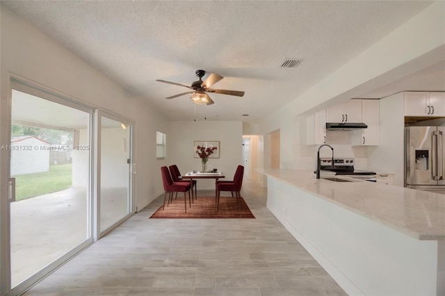 dining room with a textured ceiling, ceiling fan, plenty of natural light, and sink