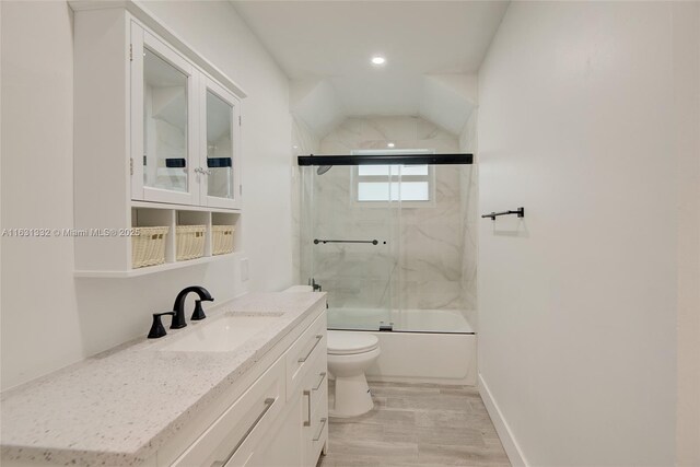 full bathroom with combined bath / shower with glass door, vanity, wood-type flooring, and toilet