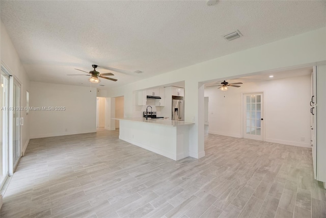 unfurnished living room featuring ceiling fan, sink, and a textured ceiling