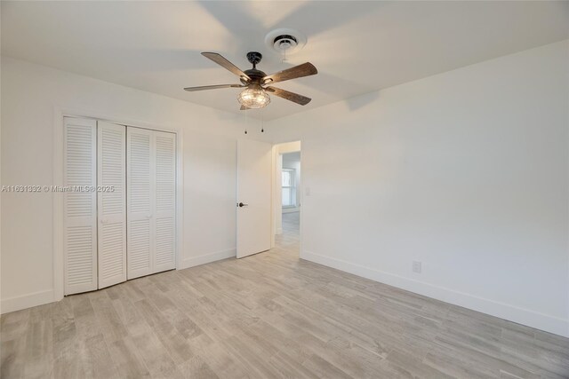 unfurnished bedroom with ceiling fan, a closet, and light wood-type flooring