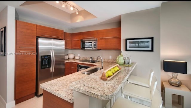 kitchen featuring appliances with stainless steel finishes, kitchen peninsula, a breakfast bar area, and sink