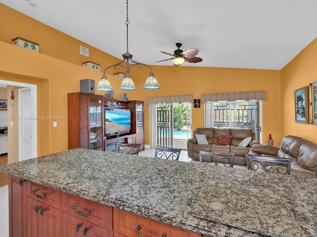 kitchen with pendant lighting, vaulted ceiling, light stone countertops, and ceiling fan