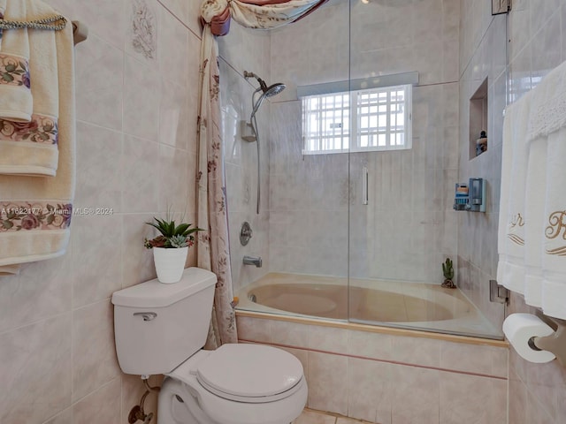 bathroom with toilet, bath / shower combo with glass door, and tile walls