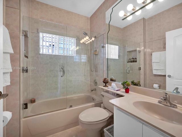 full bathroom with vanity, tile patterned floors, tile walls, combined bath / shower with glass door, and toilet