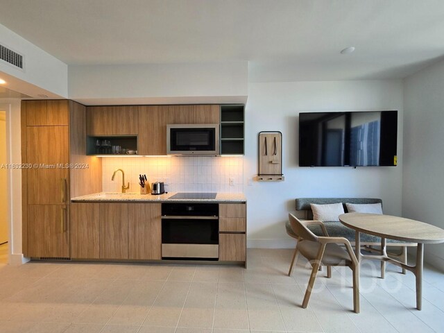 kitchen featuring decorative backsplash, appliances with stainless steel finishes, and light tile patterned floors