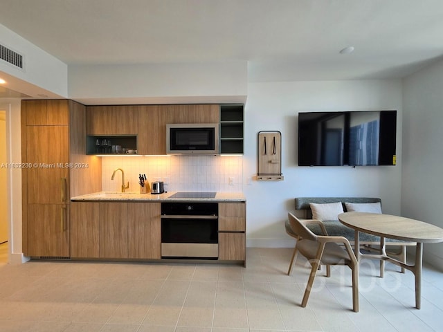 kitchen featuring stainless steel microwave, open shelves, breakfast area, and oven