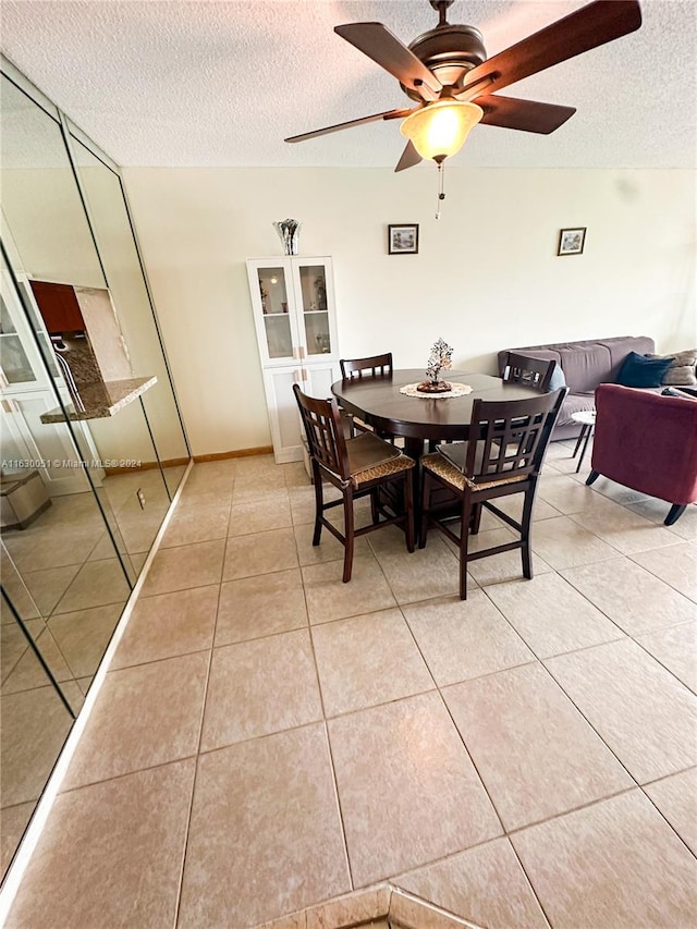 dining space with a textured ceiling, ceiling fan, and light tile patterned floors