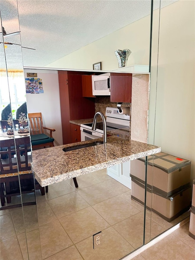 kitchen featuring a textured ceiling, light tile patterned floors, and white appliances