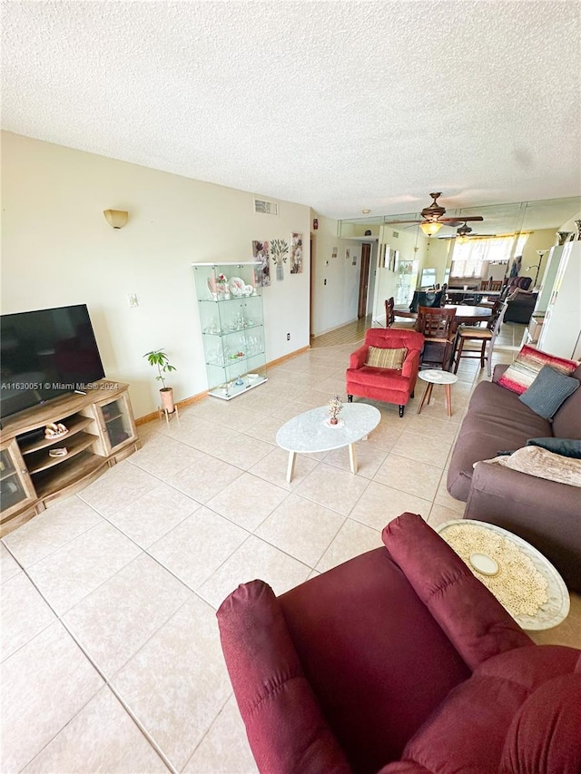 living room featuring a textured ceiling, light tile patterned floors, and ceiling fan