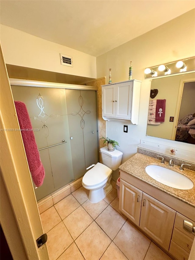 bathroom with a shower with door, vanity, toilet, and tile patterned floors