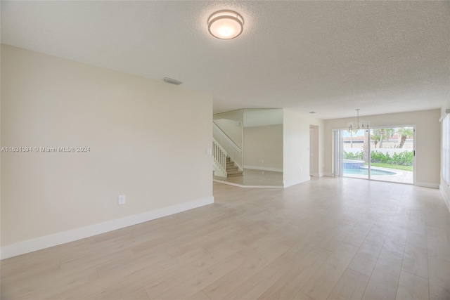13377 NW 7th St, Plantation, FL 33325 - spare room with a textured ceiling, stairway, baseboards, a chandelier, and light wood-style floors