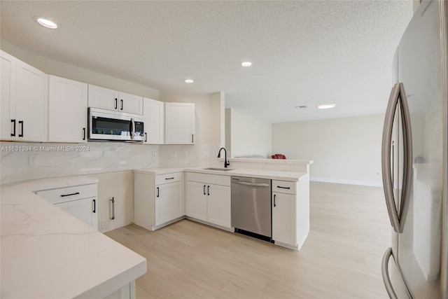 13377 NW 7th St, Plantation, FL 33325 - kitchen with light stone counters, a sink, light wood-style floors, stainless steel appliances, and a peninsula