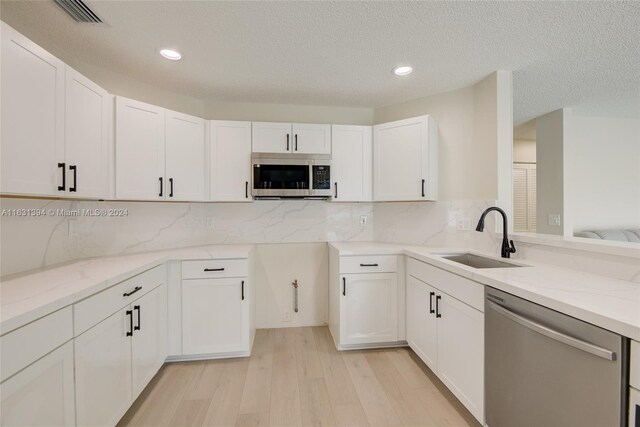 13377 NW 7th St, Plantation, FL 33325 - kitchen with appliances with stainless steel finishes, light stone counters, a sink, light wood-type flooring, and visible vents
