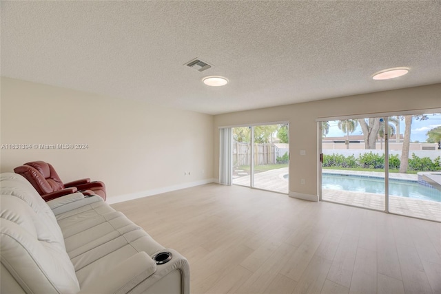 13377 NW 7th St, Plantation, FL 33325 - unfurnished living room featuring visible vents, light wood-style flooring, baseboards, and a textured ceiling