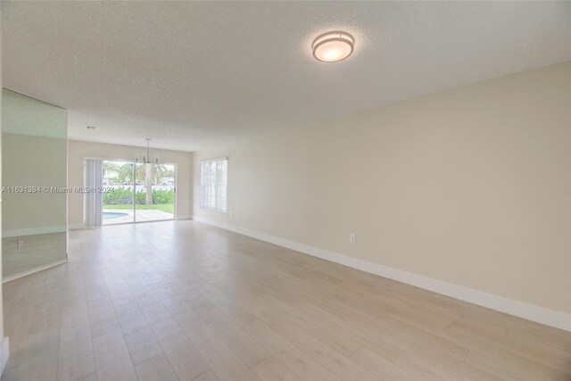 13377 NW 7th St, Plantation, FL 33325 - unfurnished room featuring an inviting chandelier, baseboards, light wood-style flooring, and a textured ceiling