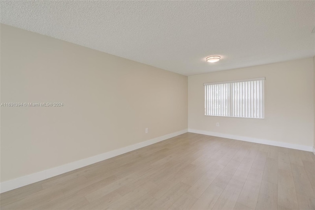 13377 NW 7th St, Plantation, FL 33325 - empty room featuring baseboards, light wood finished floors, and a textured ceiling