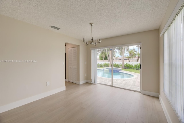 13377 NW 7th St, Plantation, FL 33325 - empty room with light wood-style floors, a notable chandelier, a textured ceiling, and visible vents
