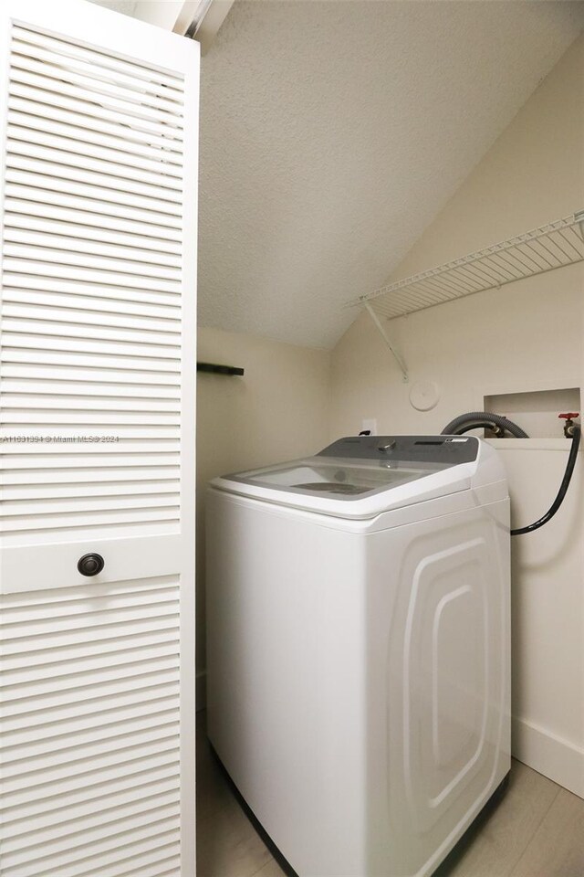 13377 NW 7th St, Plantation, FL 33325 - laundry area featuring laundry area, baseboards, light wood-style floors, washer / clothes dryer, and a textured ceiling
