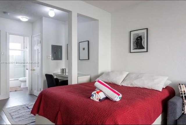 tiled bedroom featuring electric panel and connected bathroom