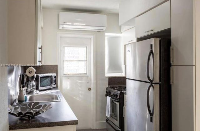 kitchen with white cabinetry, an AC wall unit, stainless steel appliances, and sink