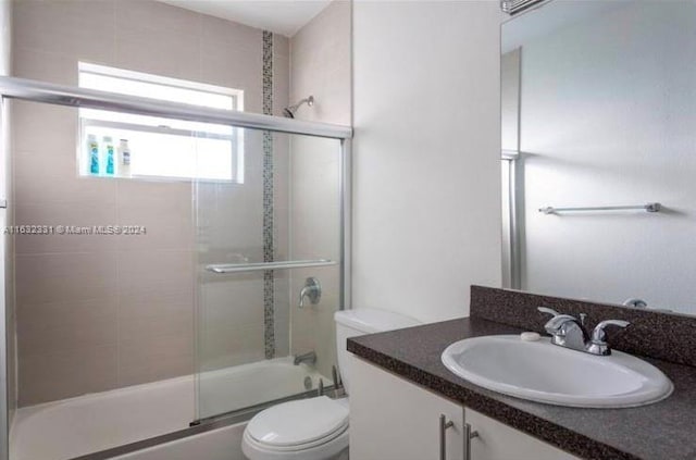 full bathroom featuring shower / bath combination with glass door, toilet, and vanity