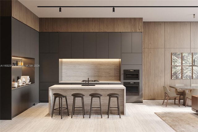 kitchen featuring sink, a center island, a kitchen bar, double oven, and track lighting