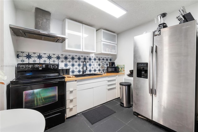 kitchen with a textured ceiling, wall chimney range hood, sink, black appliances, and white cabinetry