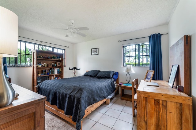 bedroom with ceiling fan, light tile patterned floors, and a textured ceiling