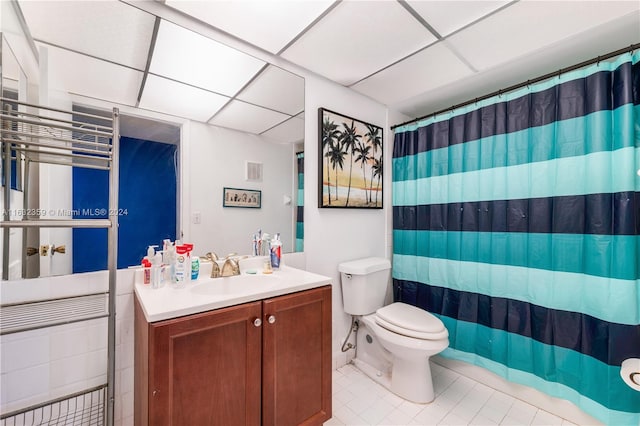 bathroom featuring vanity, toilet, and a drop ceiling