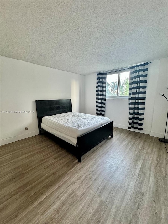 bedroom with a textured ceiling and hardwood / wood-style floors