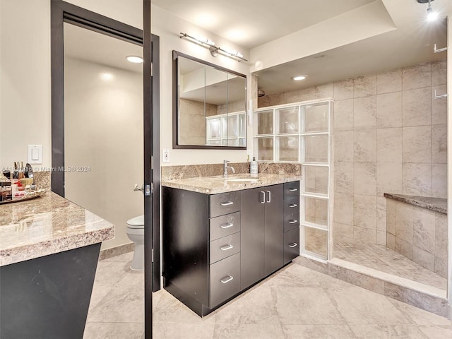 bathroom featuring tiled shower, vanity, tile patterned flooring, and toilet