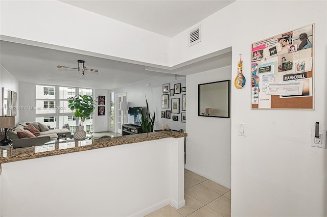 kitchen with kitchen peninsula, dark stone counters, and light tile patterned floors