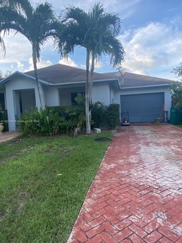 single story home featuring a garage and a front lawn