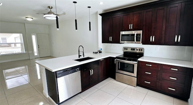 kitchen featuring appliances with stainless steel finishes, light tile patterned floors, hanging light fixtures, sink, and kitchen peninsula