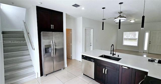 kitchen with light tile patterned flooring, stainless steel appliances, decorative light fixtures, dark brown cabinetry, and sink