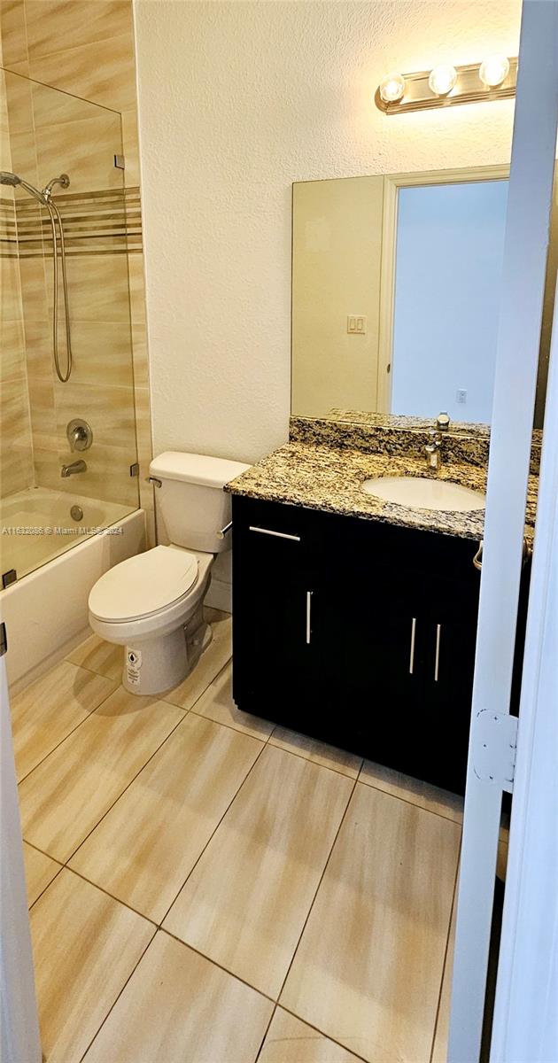 full bathroom featuring toilet, tiled shower / bath combo, vanity, and tile patterned floors