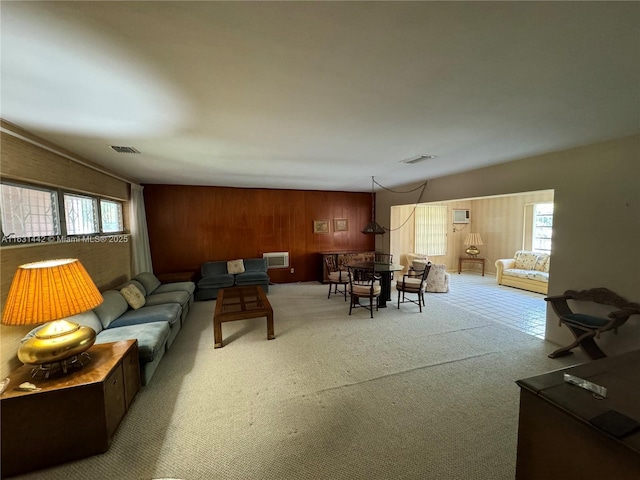 carpeted living room with wood walls, a wall unit AC, and plenty of natural light